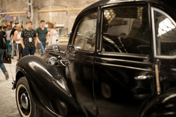 Obraz na płótnie Canvas Fragmeyn of a retro black car with close top at an exhibition 'Pin up' in the old premises of an abandoned factory in Kharkov, Ukraine, 05.19..2018
