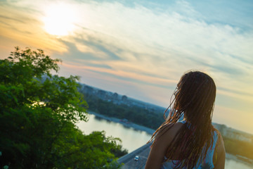 Fototapeta na wymiar Rear view of teenage girl looking to the sun / Urban sunset scene. Millennial Generation
