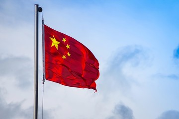 Flag of China against a blue sky.
