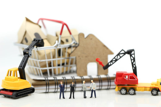 Miniature people : businessman Construction site with equipment. Crane builds a house,House in construction concept.