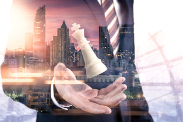 Fototapeta na wymiar The double exposure image of the businessman hold a chess king on hand overlay with cityscape image. the concept of strategic, planning, management, intelligence and education.