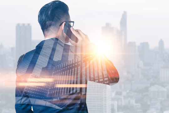 The double exposure image of the businessman using a smartphone during sunrise overlay with cityscape image. The concept of modern life, business, city life and internet of things.