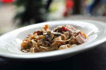 Pasta white sauce with bacon and mushroom on wood background in mystic light