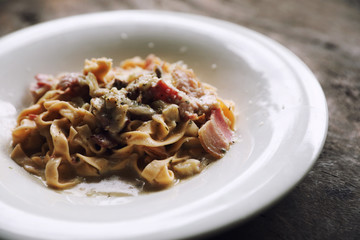 Pasta white sauce with bacon and mushroom on wood background in mystic light