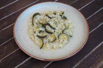 rice with zucchini in a rustic plate on a wooden table seen close up