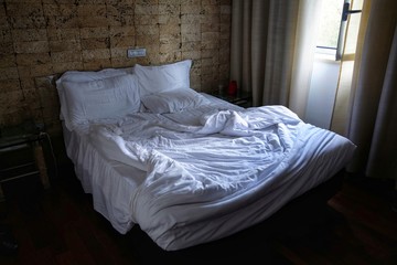empty bed and unmade at the first light of dawn - obrazy, fototapety, plakaty