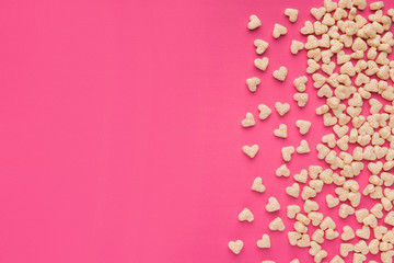 Top view of cereals in heart form on pink background