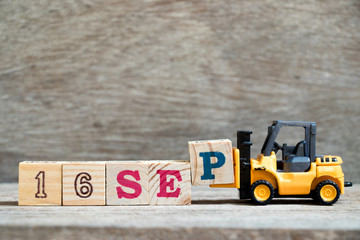 Toy forklift hold block P to complete word 16 sep on wood background (Concept for calendar date in...