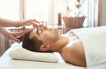 Female masseur doing head massage to man