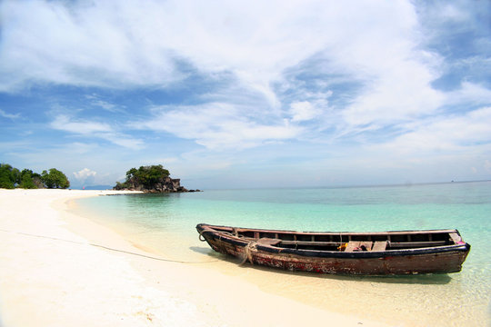 Row boat moor on the beach with blue sky and white sand