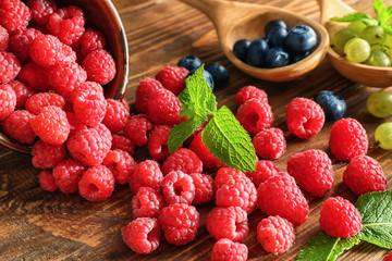 Overturned bowl with ripe raspberries on wooden table