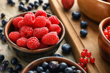 Bowl with ripe raspberries on table