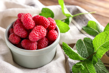Bowl with sweet ripe raspberries on table