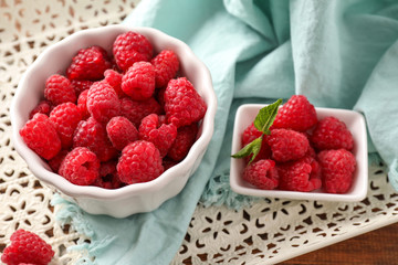 Bowls with sweet ripe raspberries on table