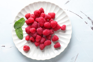 Plate with sweet ripe raspberries on table