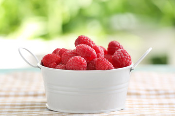 Bowl with sweet ripe raspberries on table outdoors