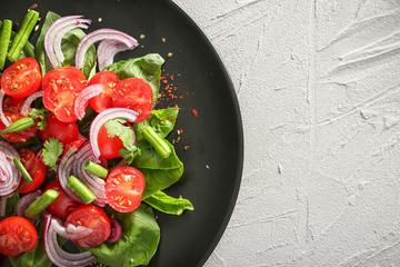 Plate with fresh vegetable salad on grey textured background