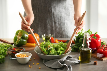 Woman preparing tasty vegetable salad in kitchen