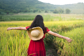Girl walking in a rice field wearing red dress