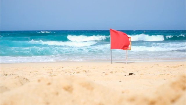 red flag on the beach for danger situation. prohibited swim activity for the big waves and tides. wind and summer strong weather in fuerteventura. colors and travel vacation concept