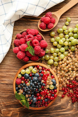 Bowls with fresh ripe berries on wooden table