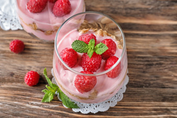 Delicious dessert with raspberries in glasses on wooden table