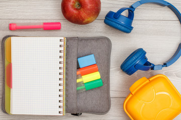 Notebook on bag-pencil case with color felt pens and marker, apple, stapler and headphones