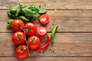 Fresh ripe cherry tomatoes, basil and chili pepper on wooden background
