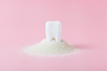 Plastic tooth in big pile of sugar.