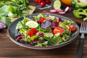 Plate with tasty vegetable salad on wooden table