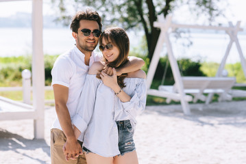 happy boyfriend cuddling girlfriend at sandy city beach