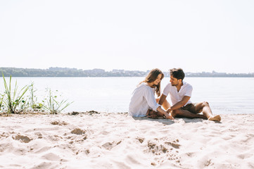 affectionate couple sitting on sandy city beach near river