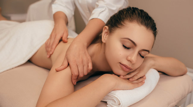 Young healthy woman receiving back massage from a massage professional at beauty salon