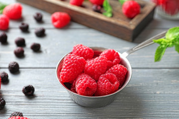 Ladle with delicious fresh ripe raspberries on wooden background