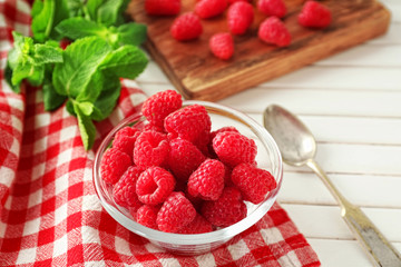 Bowl with delicious fresh ripe raspberries on table