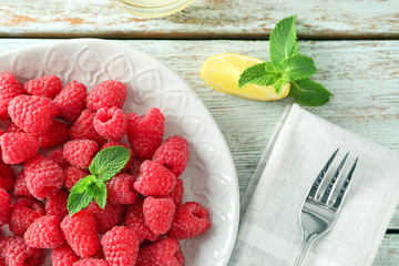 Plate with delicious fresh ripe raspberries on wooden table