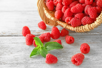 Basket with delicious fresh ripe raspberries on wooden background