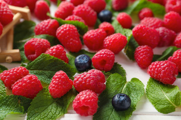 Delicious fresh ripe raspberries and blueberries on light background
