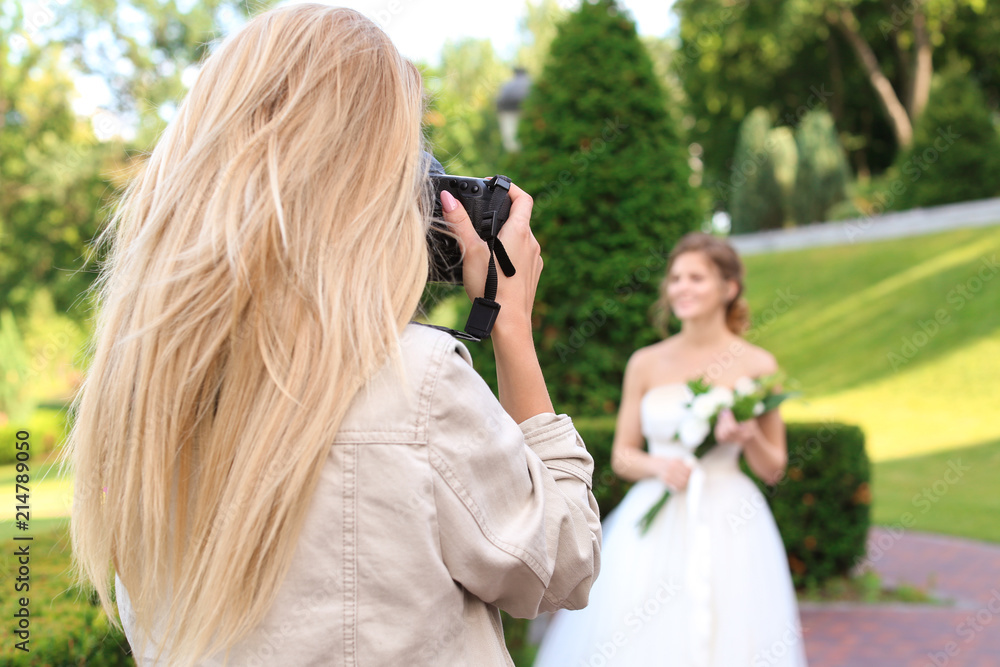 Wall mural Professional photographer taking photo of beautiful bride outdoors