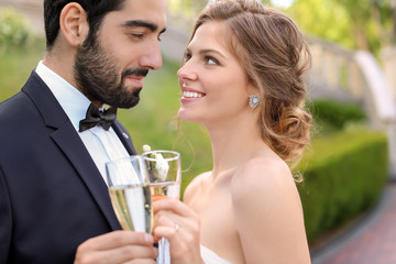 Happy wedding couple with glasses of champagne outdoors