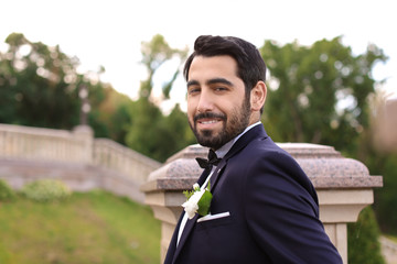 Handsome young groom in elegant suit outdoors