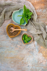 Fresh and Dried Basil in Small Heart-Shaped Bowls on Plaster Background