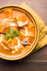 Paneer Butter Masala also known as Panir  makhani or makhanwala. served in a ceramic or terracotta bowl with fresh cream and coriander. Isolated over colourful moody background. selective focus
