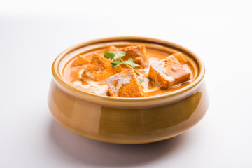 Paneer Butter Masala also known as Panir  makhani or makhanwala. served in a ceramic or terracotta bowl with fresh cream and coriander. Isolated over colourful moody background. selective focus
