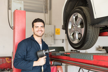 Automobile Expert Holding Impact Wrench By Car On Lift