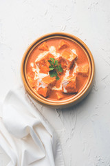 Paneer Butter Masala also known as Panir  makhani or makhanwala. served in a ceramic or terracotta bowl with fresh cream and coriander. Isolated over colourful moody background. selective focus