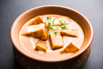 Paneer Butter Masala also known as Panir  makhani or makhanwala. served in a ceramic or terracotta bowl with fresh cream and coriander. Isolated over colourful moody background. selective focus