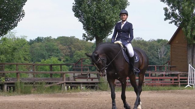 a young girl jockey riding a horse in a sand circle. Sunny day. empty arena for dressage. strong muscular horse tired. Slow motion Fool HD
