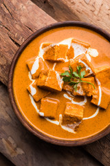 Paneer Butter Masala also known as Panir  makhani or makhanwala. served in a ceramic or terracotta bowl with fresh cream and coriander. Isolated over colourful moody background. selective focus