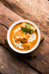 Paneer Butter Masala also known as Panir  makhani or makhanwala. served in a ceramic or terracotta bowl with fresh cream and coriander. Isolated over colourful moody background. selective focus